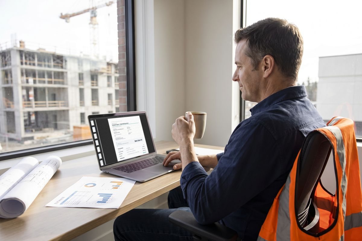Estimator at a desk reviewing a finished BIM-IQ estimate report on a laptop